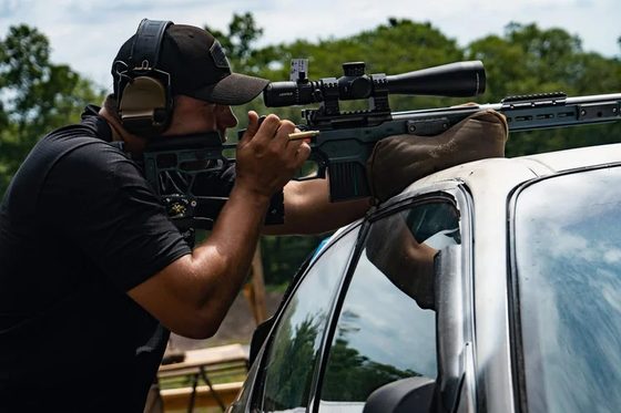 Jacob Zupke aiming a precision rifle from the bed of a truck