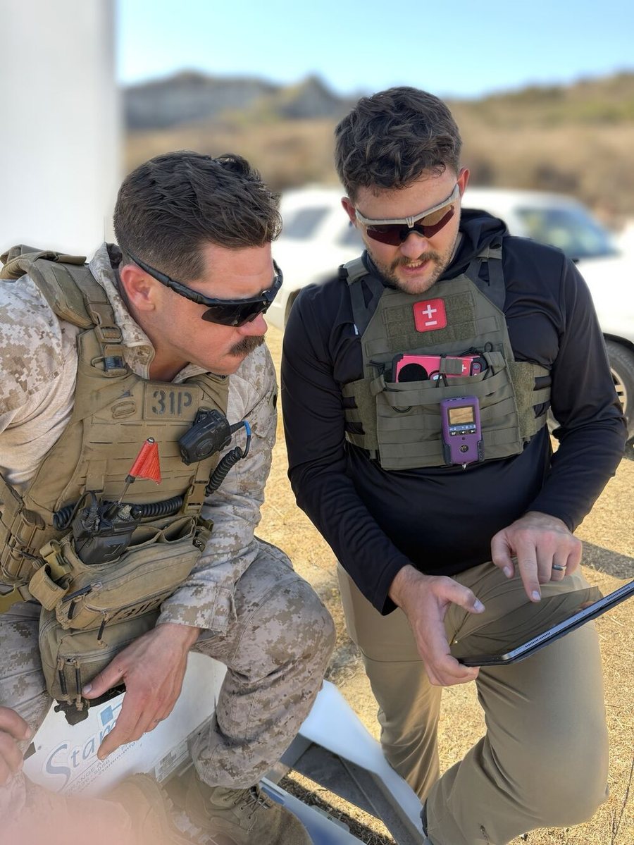 A Marine and a Scoring Tech team member reviewing shot data on a tablet at the range